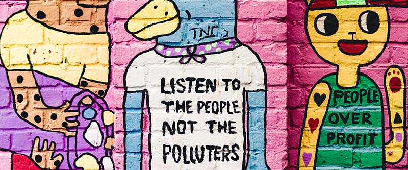 street art of two animal figures with graphic teeshigraphic street art stating 'listen to the people not the polluters'