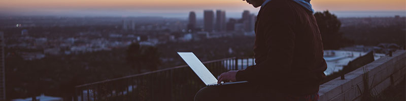 A man using a laptop overlooking the city
